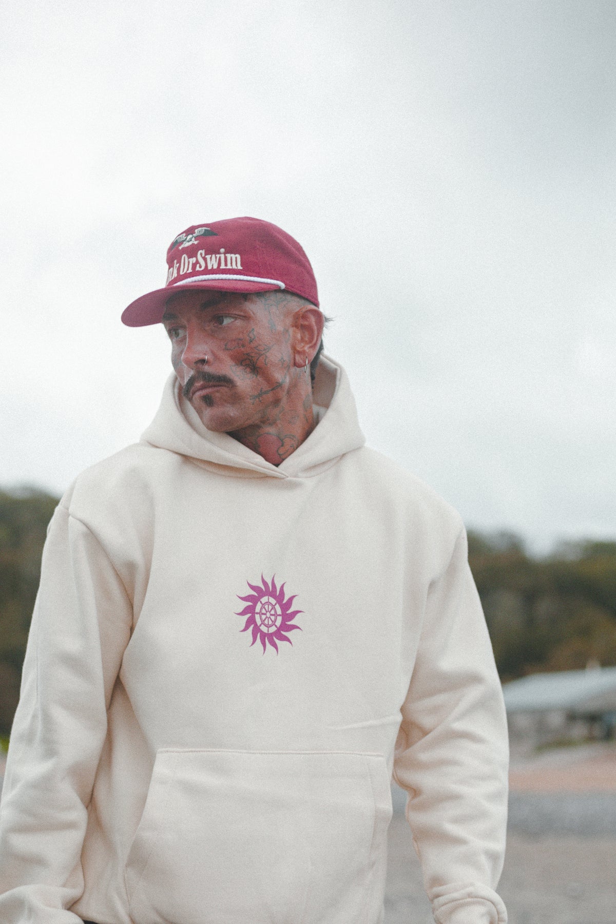 Man in the oversized vanilla Neon Sun Wheel heavyweight hoodie and red Vintage Eagle cord rope cap
