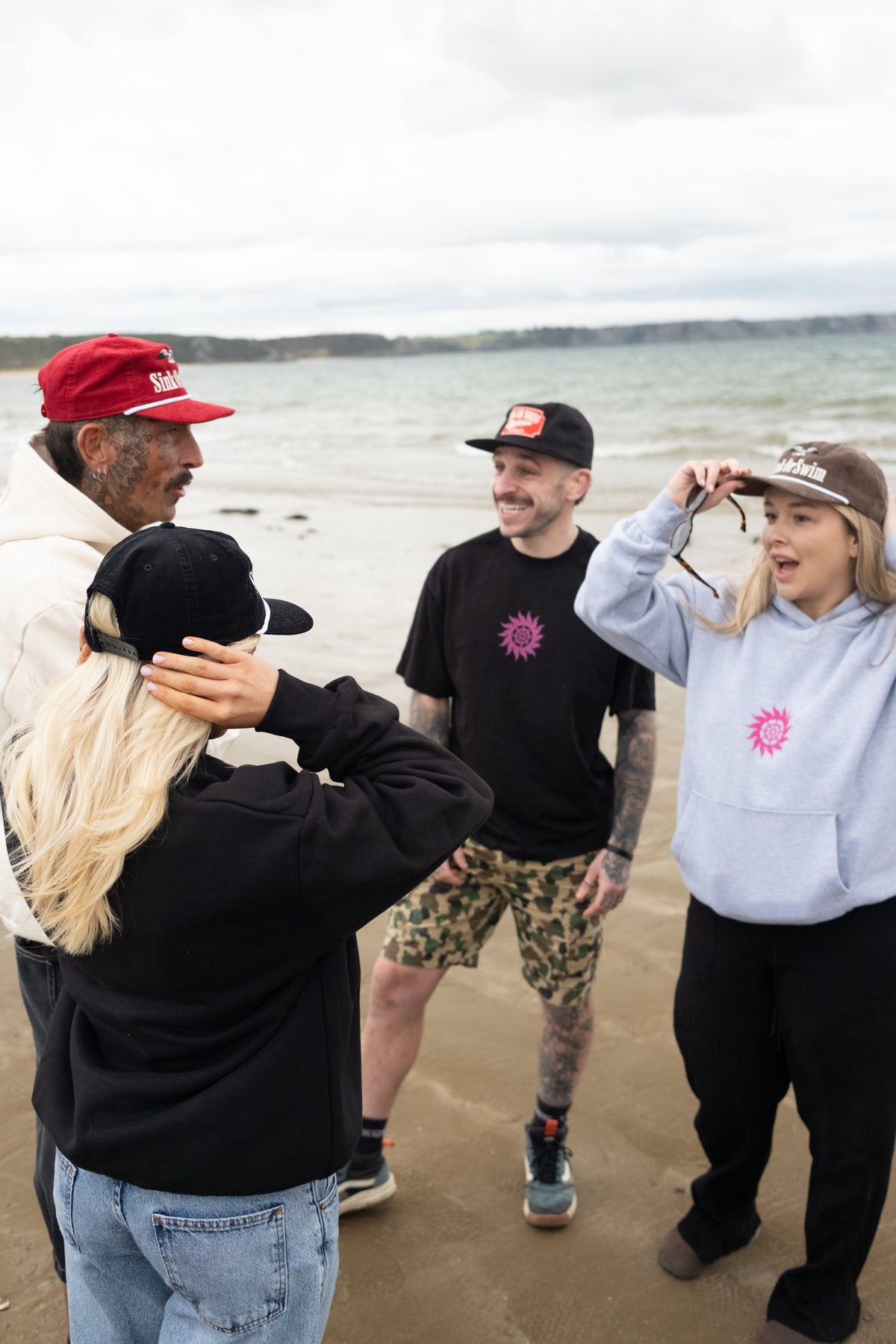 Friends on the beach in red and brown Vintage Eagle cord rope caps, a black Vintage Tiger cap and Neon Sun Wheel hoodies