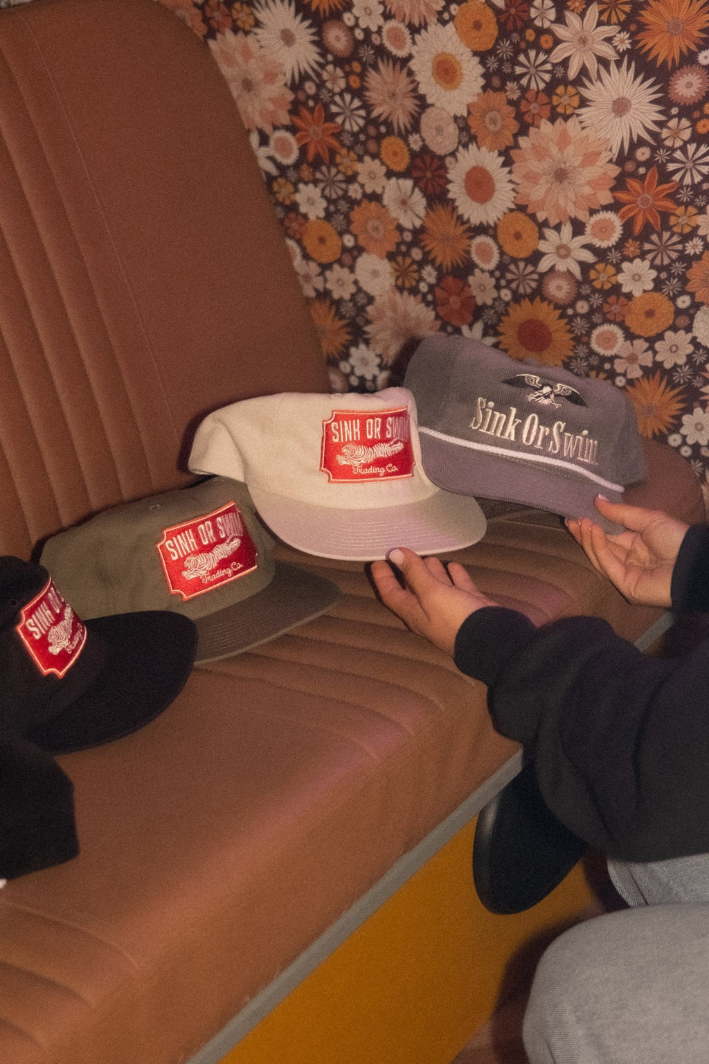 Hand holding the raw Vintage Tiger 5 panel cap by black and army green Tiger caps and the grey Eagle cord cap in a retro van